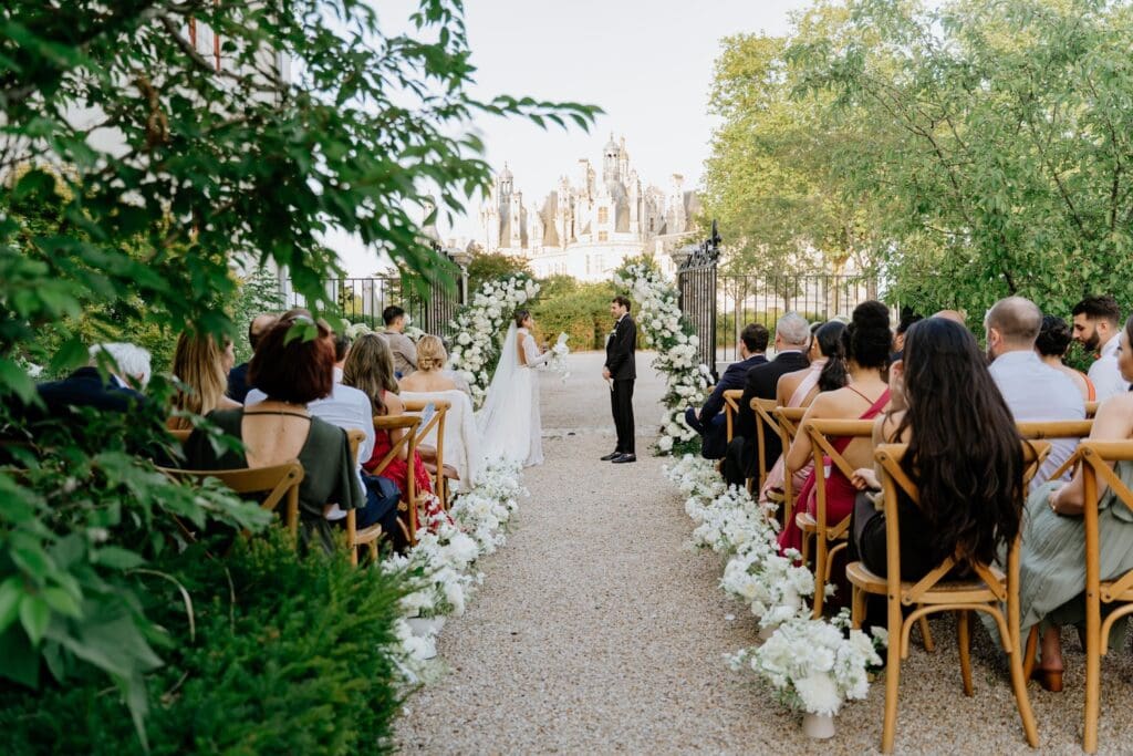 Arche de cérémonie avec scénographie florale poétique et feuillages naturels.